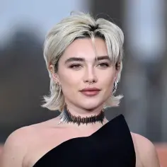 Krótkie, blond włosy z grzywką i kolczykami nawiązują do modnych fryzur lat 80.