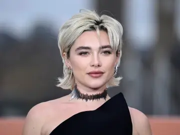 Krótkie, blond włosy z grzywką i kolczykami nawiązują do modnych fryzur lat 80.