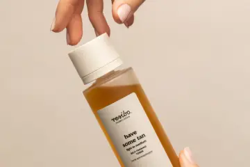 Dłoń trzyma buteleczkę toniku samoopalającego z dihydroxyacetone. Efekt muśnięcia słońcem.